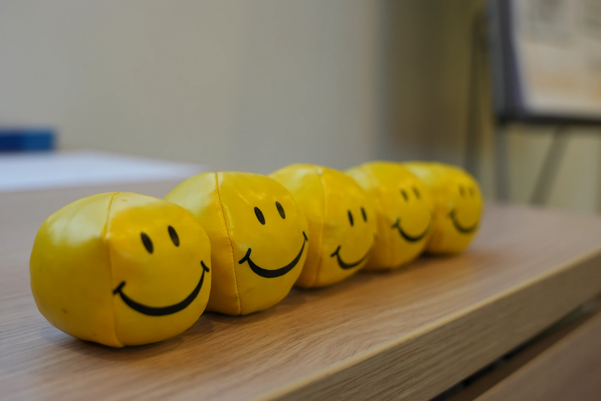 Fünf gelbe Smiley-Bälle auf einem Holztisch