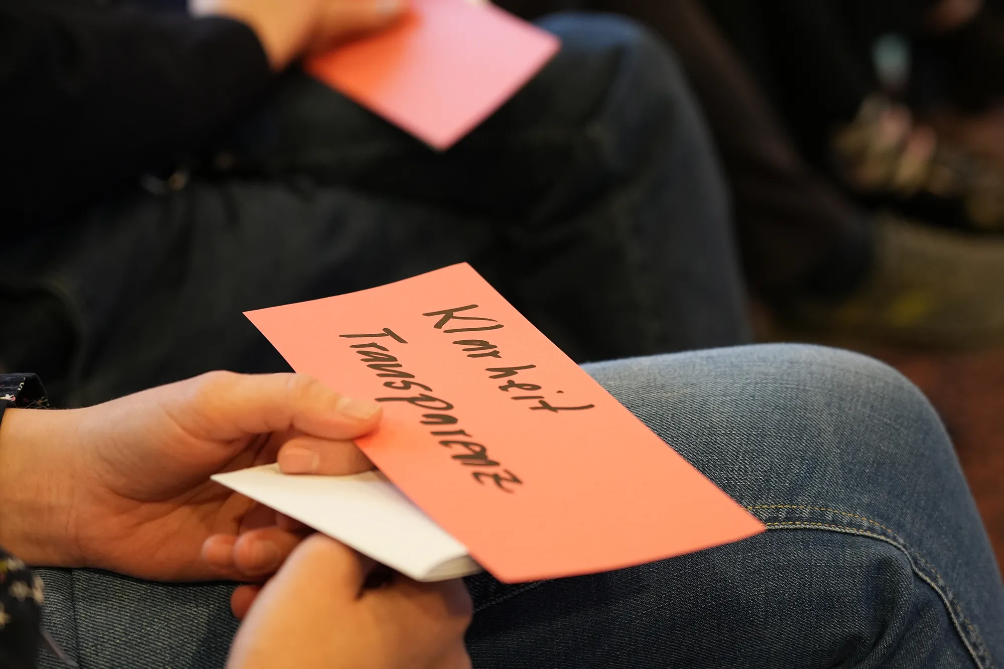 Person hat einen Zettel in der Hand, wo Klarheit und Transparenz drauf steht